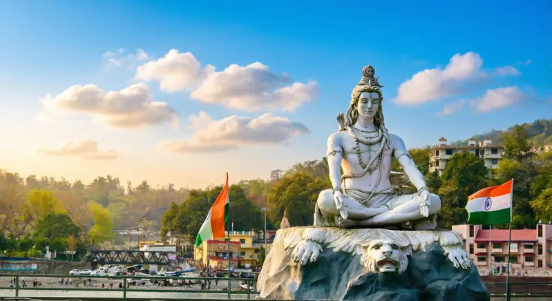 Cтатуя Господа Шивы, расположенная на берегу реки Ганг в городе Ришикеш, Индия. Это место известно как Тривени Гхат, популярное место для паломничества и проведения индуистских ритуалов, таких как Ганга Аарти.