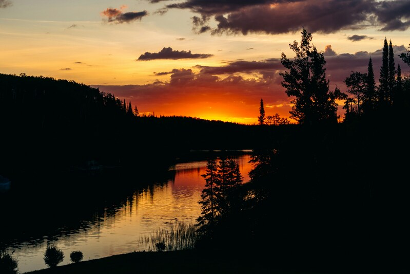 Cпокойный закат над рекой или озером, окруженным лесом