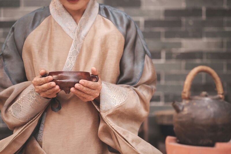 Девушка в традиционной одежде держит глиняную чашу